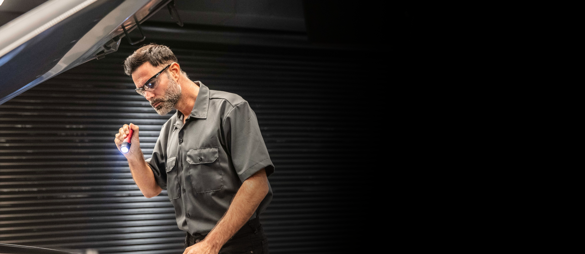 Service technician inspecting a vehicle in a service bay.
