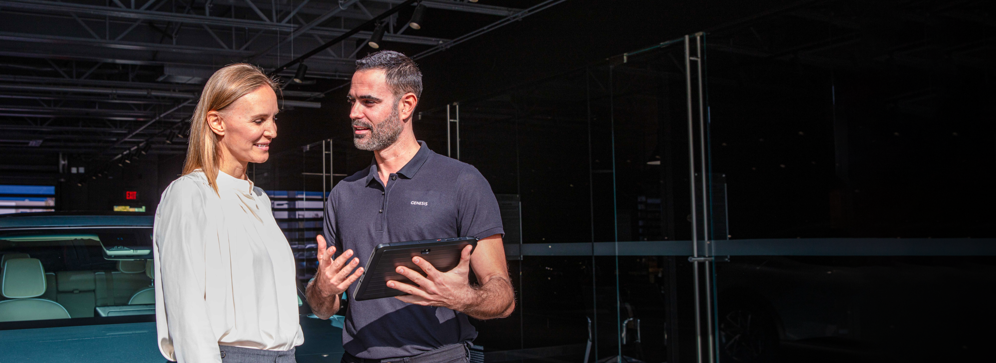 Genesis service advisor speaking with customer inside dealership.