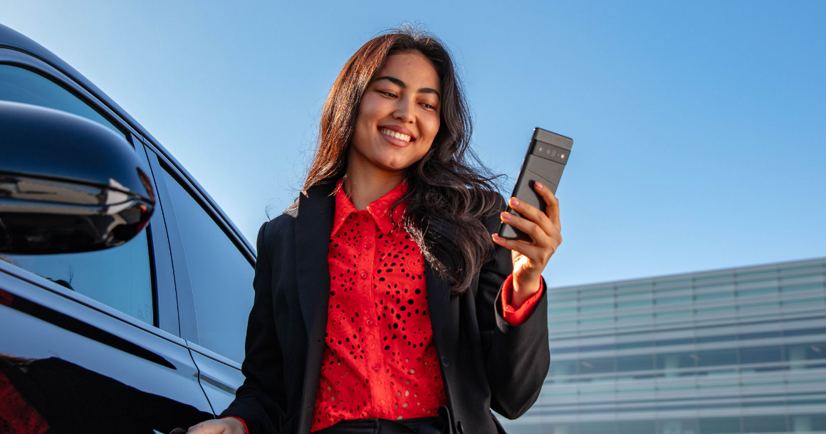 Driver using Genesis Connected Services app beside Genesis vehicle.