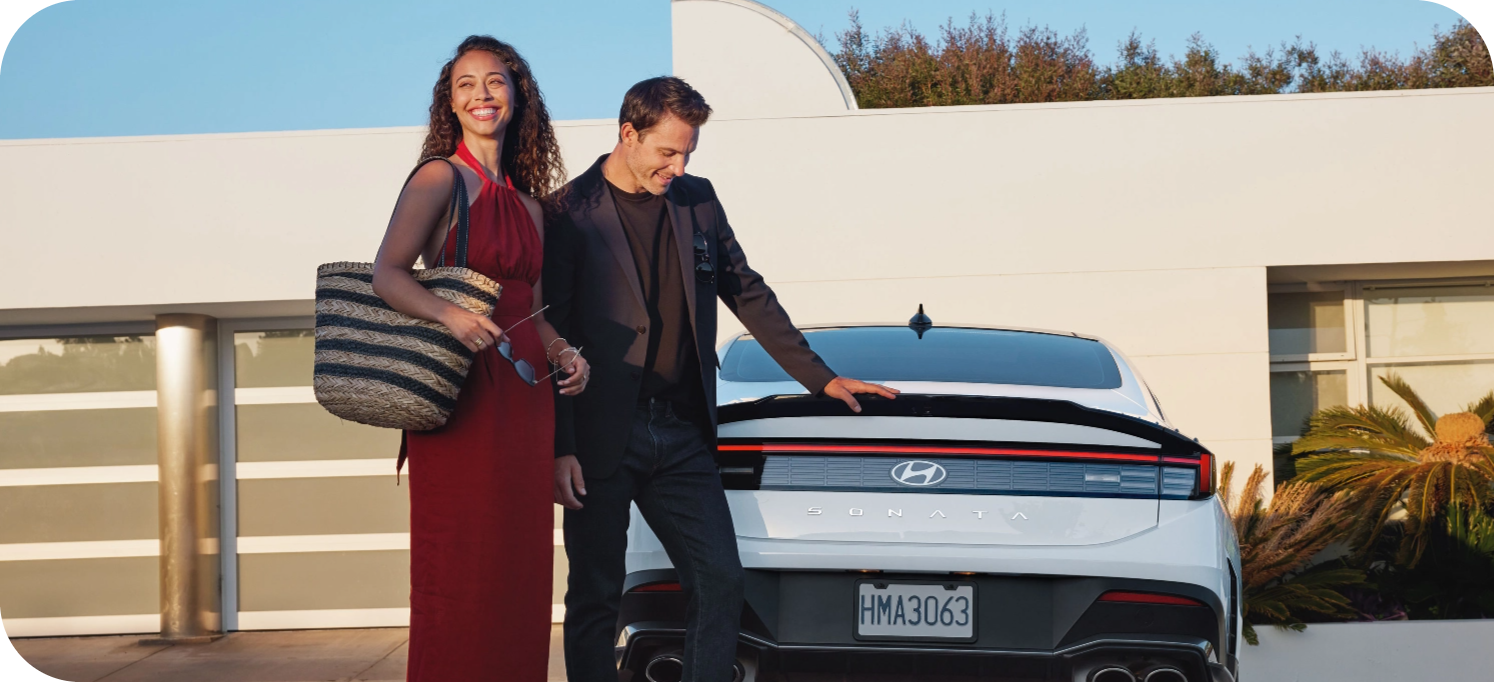 Couple standing beside a Hyundai Sonata outside a home