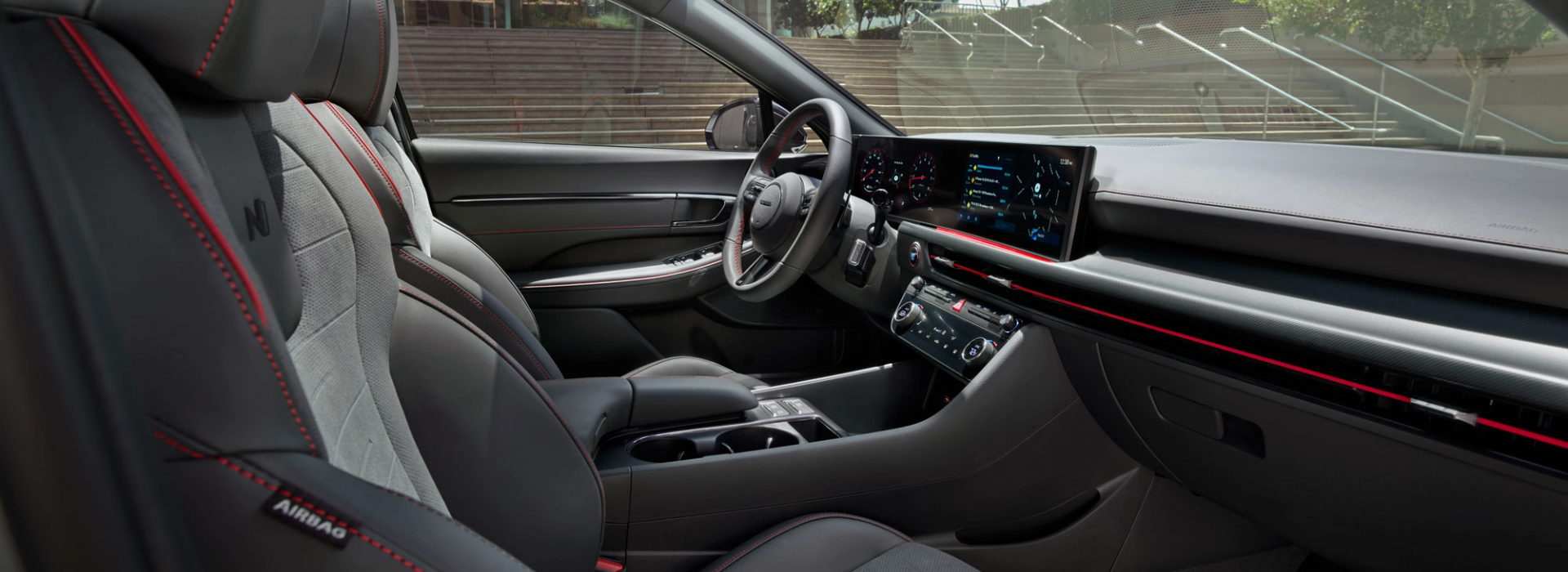 Sporty Hyundai cabin with red contrast stitching, digital dash display, and ambient interior lighting.