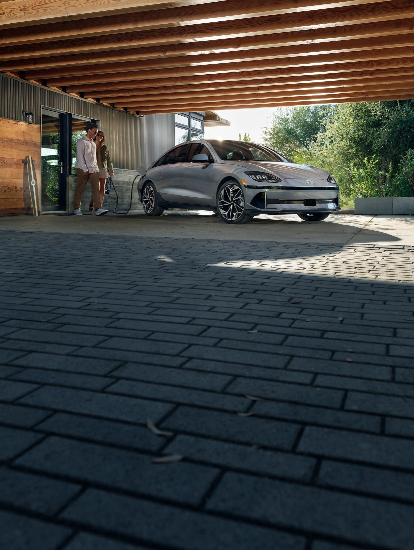 Couple walking near a Hyundai EV charging at home.