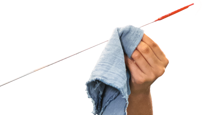 Person holding an oil dipstick with a red tip, wiping it with a blue cloth.