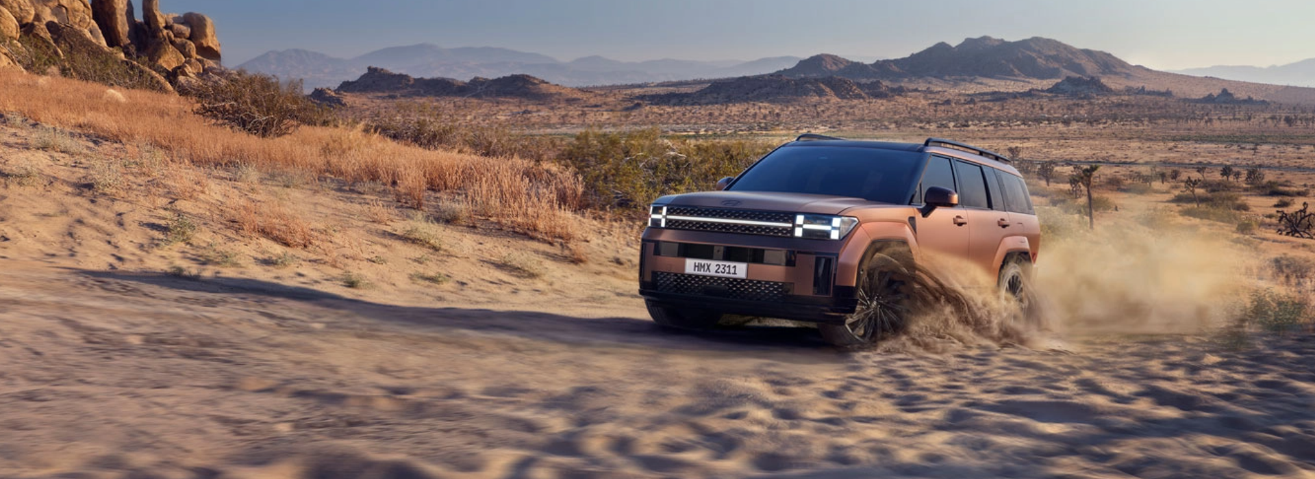 Hyundai SUV kicking up dust while off-roading in a desert setting.