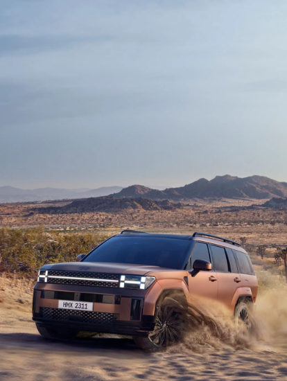 Hyundai SUV kicking up dust while off-roading in a desert setting