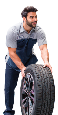 Smiling Hyundai technician in uniform rolling a tire during service