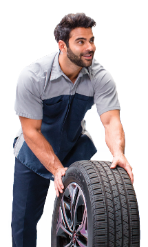 Smiling Hyundai technician in uniform rolling a tire during service