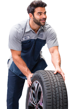 Smiling Hyundai technician in uniform rolling a tire during service