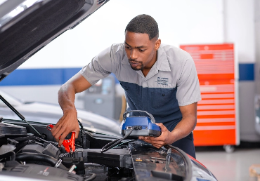 Hyundai technician testing a vehicle battery with diagnostic equipment
