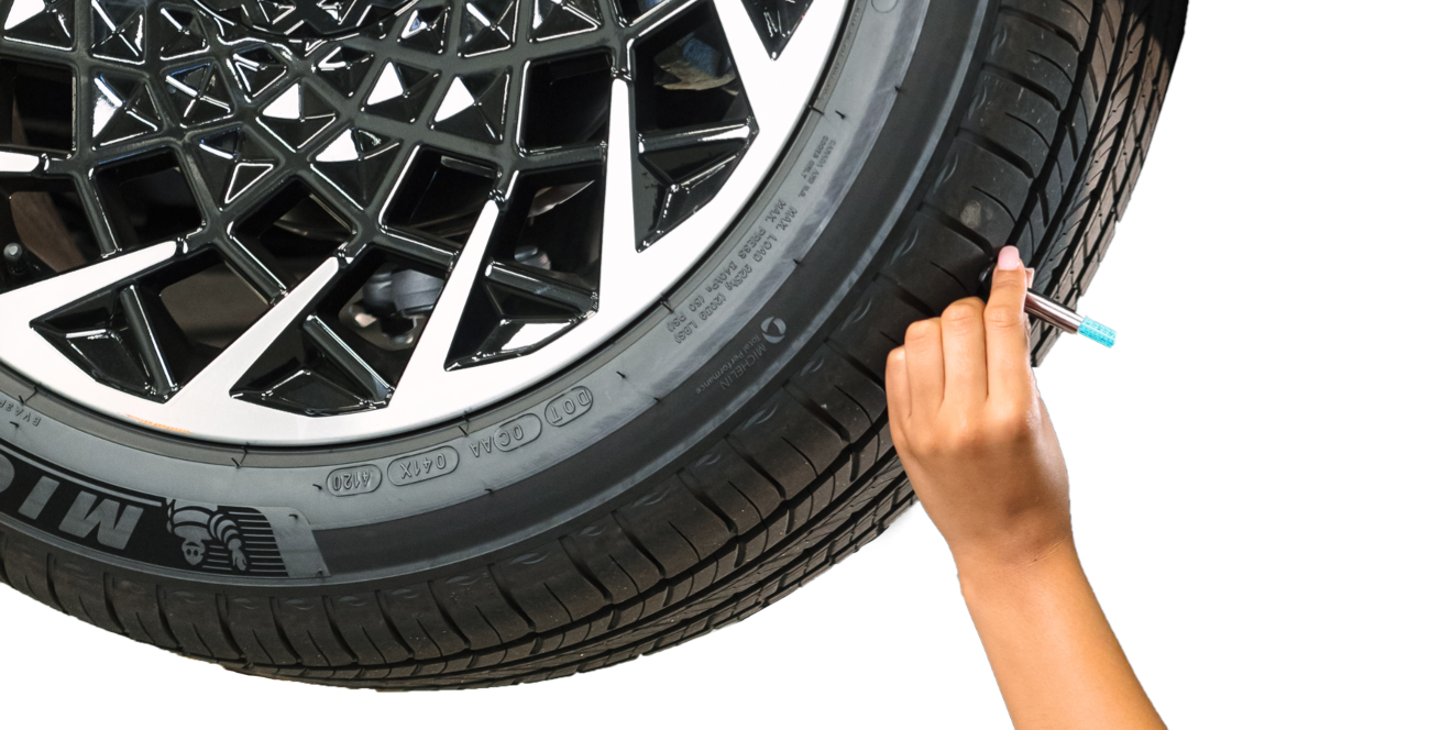Hand measuring tire tread depth with a gauge tool