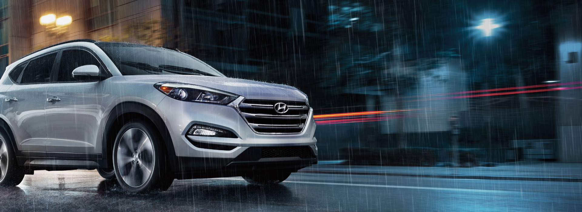 Hyundai SUV driving in heavy rain with wipers in motion.
