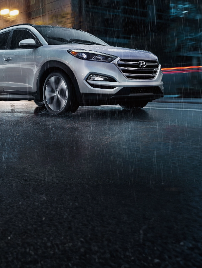 Hyundai SUV driving in heavy rain with wipers in motion.
