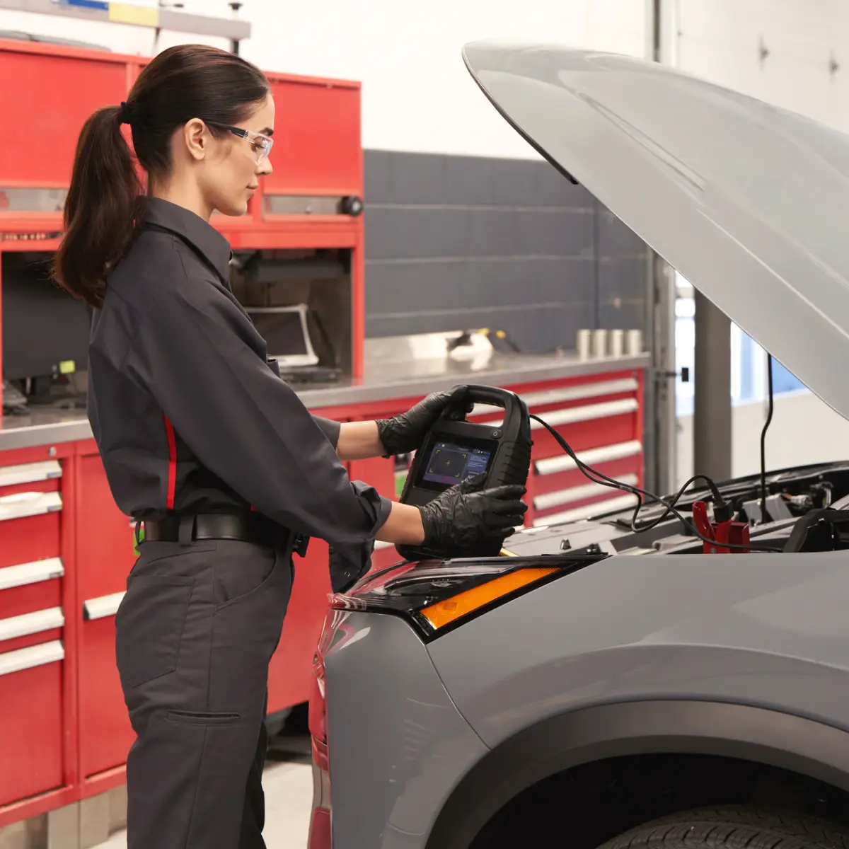 Nissan-trained technician testing car battery health with compact battery testing device