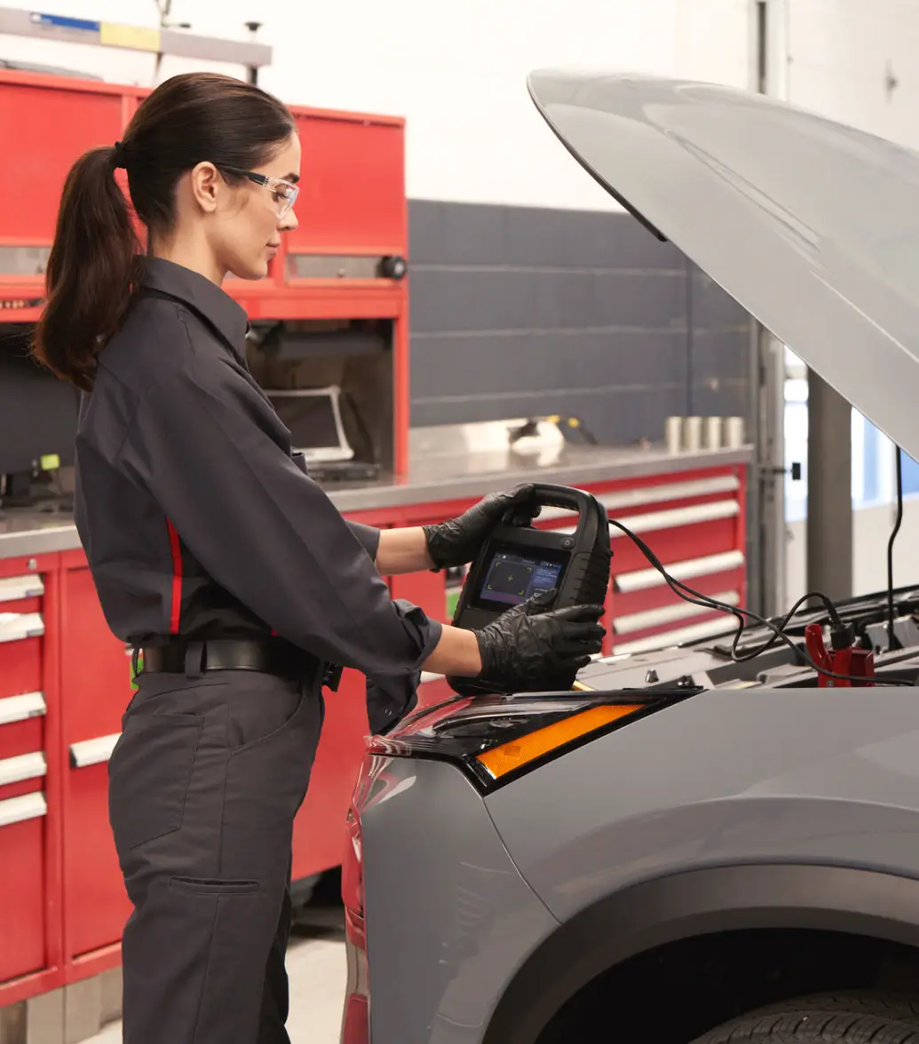 Nissan-trained technician testing car battery health with compact battery testing device