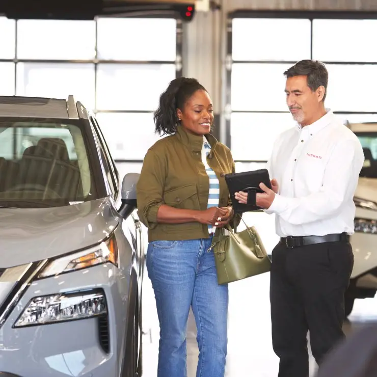 Nissan service advisor sharing sucessful service results on a tablet device with a happy customer