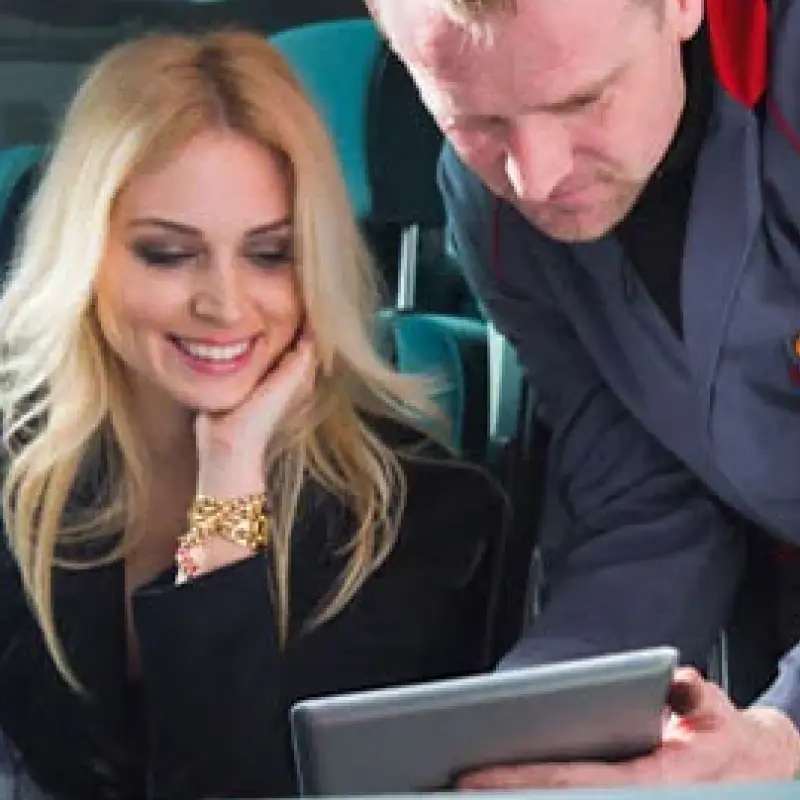 A smiling woman and a technician looking at a tablet together.
