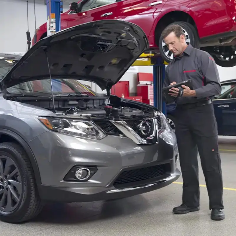 Nissan-trained technician performing a multi-point vehicle inspection in garage