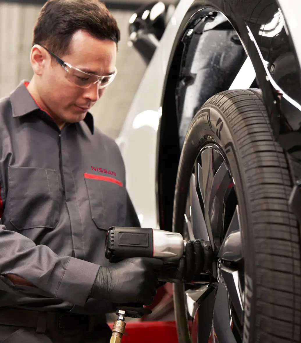 Nissan Price Assurance logo with Nissan-trained technician installing tire on car